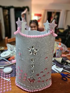 a silver crown with pink beads on it sitting on top of a table next to scissors