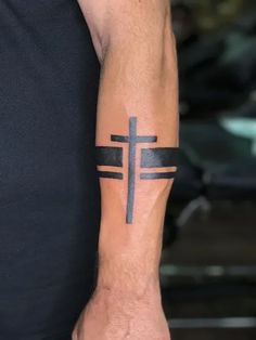 a man's arm with a cross tattoo on the side of his left arm