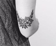 a black and white photo of a woman's foot with flowers tattooed on it