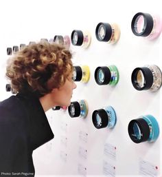 a person standing in front of a white wall with many different colored cups on it