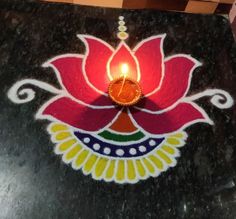 a lit candle sitting on top of a black table next to a flower shaped object