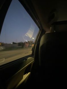 the view from inside a car driving down a highway at night with buildings in the distance