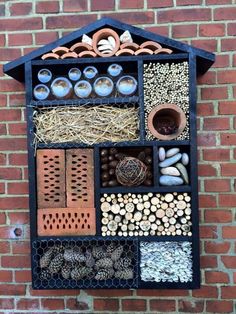 a building made out of different types of items on a brick wall with holes in it