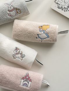 three towels with cartoon characters on them are lined up next to each other and one has a toothbrush in it