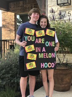 two people standing next to each other holding a sign that says you are one in a melon hoco