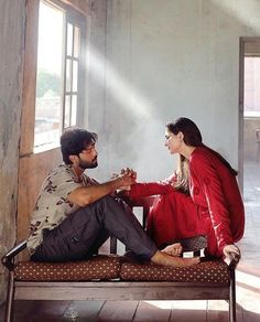 a man and woman sitting on a bench in an old building with sunlight streaming through the windows