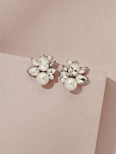 two pairs of pearl and crystal flower earrings on top of a piece of pink paper