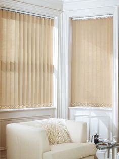 a white couch sitting in front of two windows with blinds on it's sides