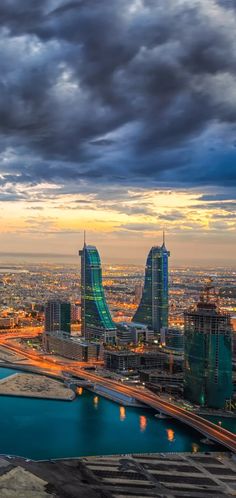 an aerial view of a city at sunset with clouds in the sky and water below