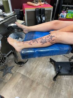 a woman is sitting in a chair with her legs crossed and tattoo on the leg