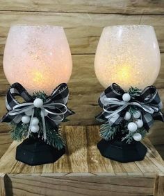 two wine glasses decorated with bows and lights