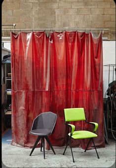 two chairs sitting next to each other in front of a red curtain with black legs