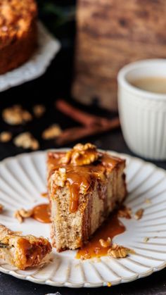 a piece of cake sitting on top of a white plate next to a cup of coffee