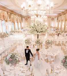 a bride and groom are standing in the middle of a banquet hall with tables set up for formal function