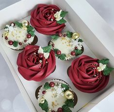 four cupcakes in a box decorated with red roses and gold ornaments on them