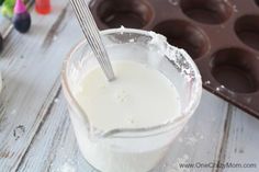 a cup filled with white liquid next to chocolate muffins