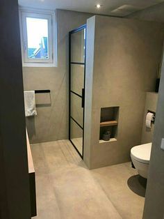 a bathroom with a toilet, sink and shower in it's center wall next to a window