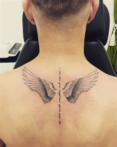 the back of a man's neck with two birds on it and a cross in the middle