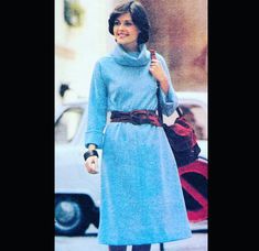 a woman walking down the street in a blue dress and brown belted boots, holding an umbrella