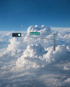 a street sign on top of a traffic light above the clouds