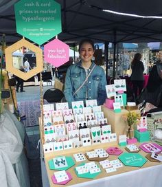 a woman standing in front of a table full of cards and greeting cards for sale