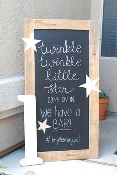 a chalkboard sign on the side of a building that says, two little stars come on in we have a bar