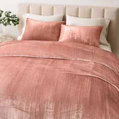 a bed with pink sheets and pillows on top of it