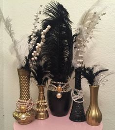 there are several vases with pearls and feathers on the shelf in front of the wall