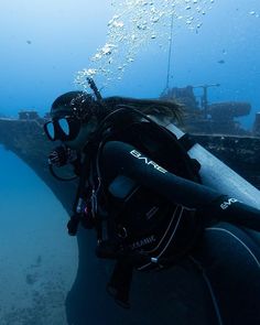 a woman scubas in the water near a boat