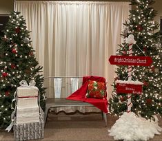 christmas trees and presents are displayed in front of a window with white drapes on the windowsill