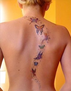 the back of a woman's tattoo with butterflies on her upper and lower back