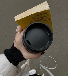 a person holding a coffee cup with a book in their hand