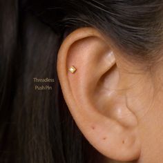 a woman's ear is shown with two small gold studs