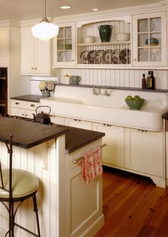 a kitchen with white cabinets and an island in front of a stove top oven next to a sink