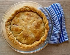 a pie sitting on top of a wooden table next to a blue and white towel