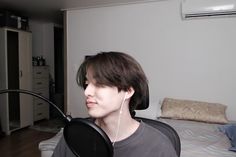 a young man with headphones on his ears listening to music in front of the bed