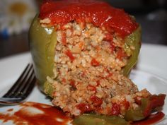 a stuffed green pepper sitting on top of a white plate