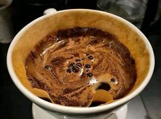 a cup filled with liquid sitting on top of a white saucer covered in chocolate