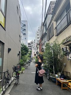 a woman is standing in the middle of an alleyway with bicycles parked on both sides