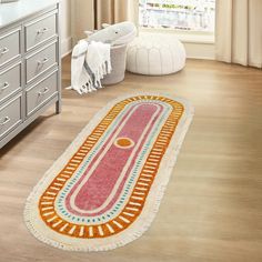 a bathroom rug with an orange and pink design on the floor in front of a window