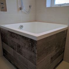 a bathroom with a large white bathtub next to a window