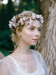 a woman wearing a flower crown in front of a tree