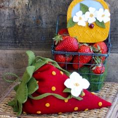 strawberries and flowers are sitting in a basket next to a decorative pillow on a table