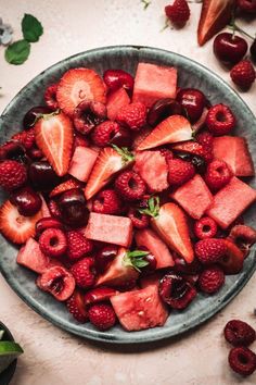 a bowl filled with strawberries, raspberries and watermelon cubes