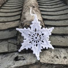 a white crocheted snowflake sitting on top of a brick wall next to a roof