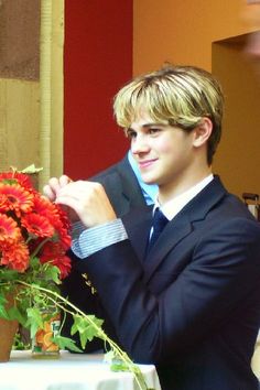 a young man in a suit is arranging flowers