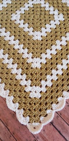 a brown and white crocheted blanket sitting on top of a wooden floor