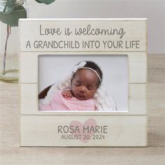 a wooden frame with a baby's photo and the words love is welcoming, a grandchild into your life