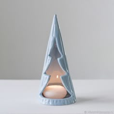 a small blue candle holder with a lit candle in the shape of a christmas tree