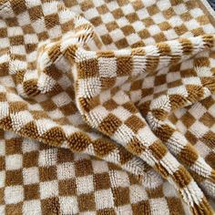 a brown and white checkered blanket laying on top of a bed